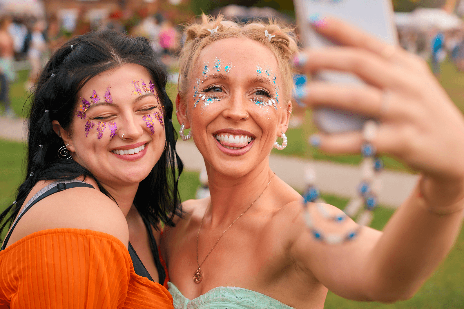 Friends taking a glitter-covered selfie at an outdoor festival